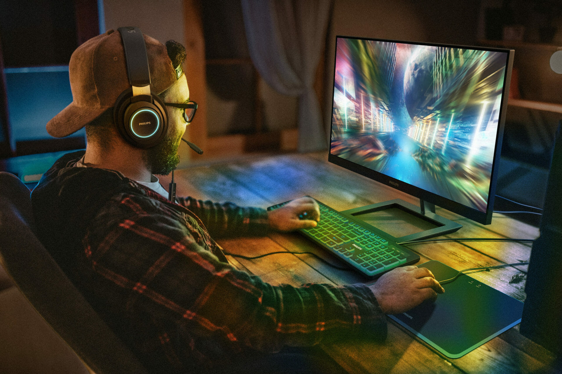 Man with headphones playing a game in front of a philips monitor