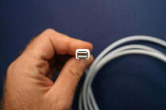 A man hand holding a thunderbolt cable